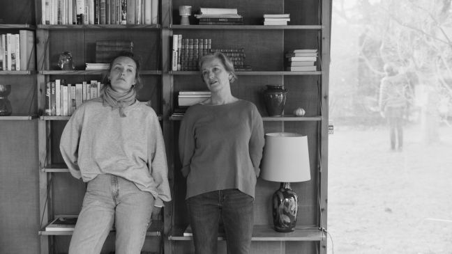 Tochter und Mutter stehen vor dem Bücherregal