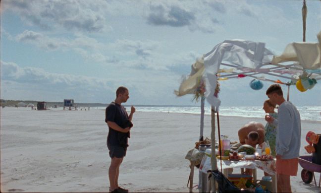 Danielius steht mit Freunden am Strand und bereitet ein Essen vor