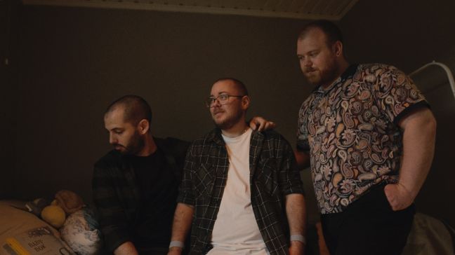 Kristopher, David und Sindre stehen in einem Kinderzimmer und schauen liebevoll