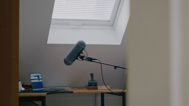 Ein Schreibtisch, darauf ein Laptop, darüber ein Mikrofon im Windkorb