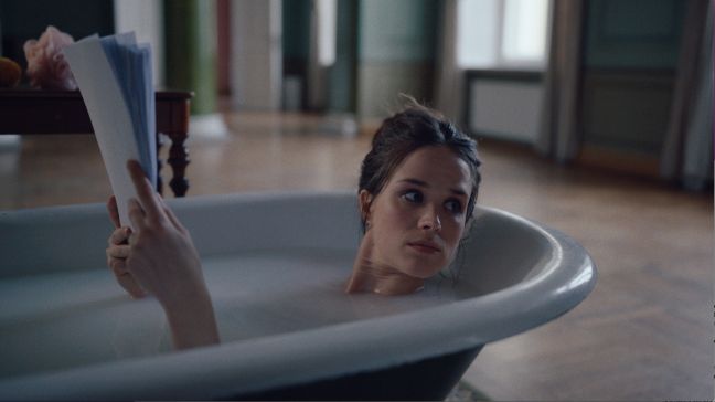 Die Tyrannin liegt abends in der Badewanne und liest aus ihrem Filmscript, schaut in Richtung Tür