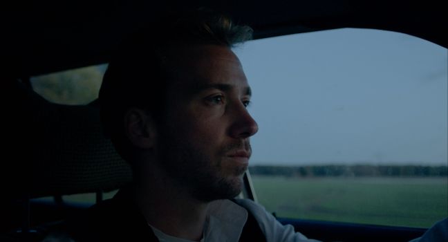 Nahaufnahme Paul abends im Auto, ernster Blick