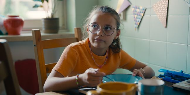 Teresas Tochter schaut ihre Mutter an und isst Müsli