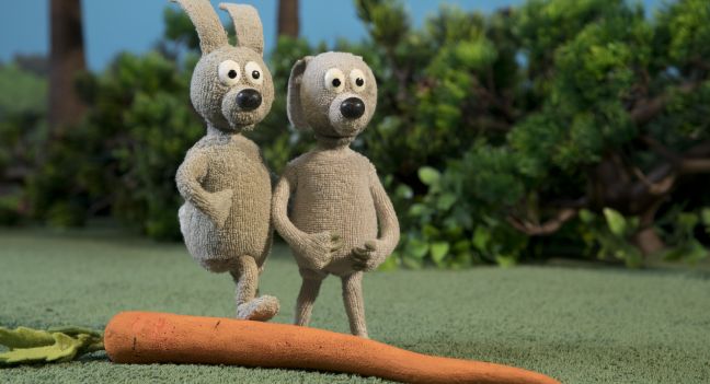 Zwei Hasen stehen bei der Karotte, einer hat den Fuß auf dieser