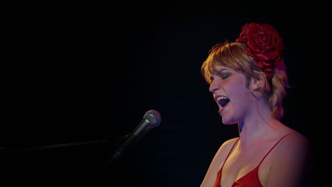 Nahaufnahme Lydmor singend auf der Bühne, mit Rose in den Haaren