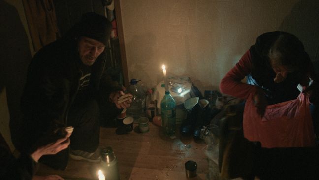 Ein Mann und eine Frau sitzen auf dreckigem Boden, Essen, Trinken und Suchen in einer Tasche