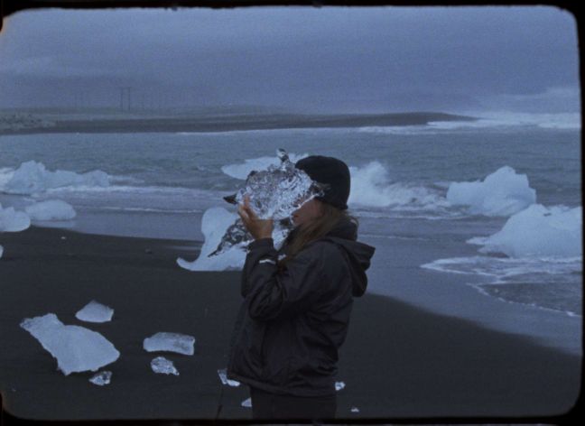 Eine Frau hält ein großes Stück Eis vor ihr Gesicht
