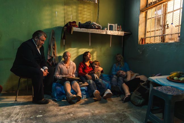 Ida, drei weitere Frauen, ein Kind und ein Mann in einer Gefängniszelle