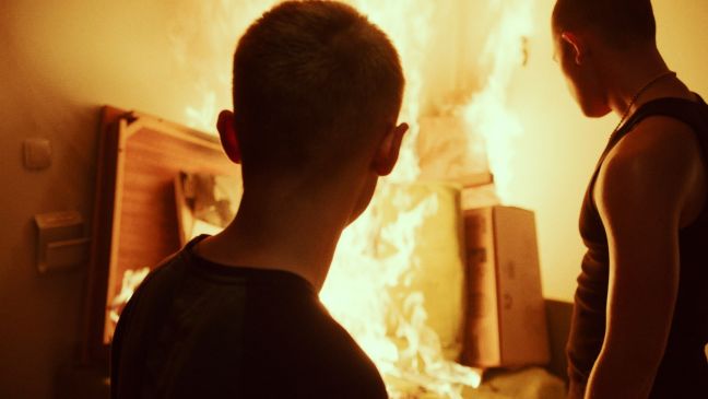 Robin und Dennis stehen vor brennendem Sperrmüll