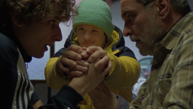 Marko beim Armdrücken mit seinem Vater, sein Bruder beaufsichtigt den Wettkampf