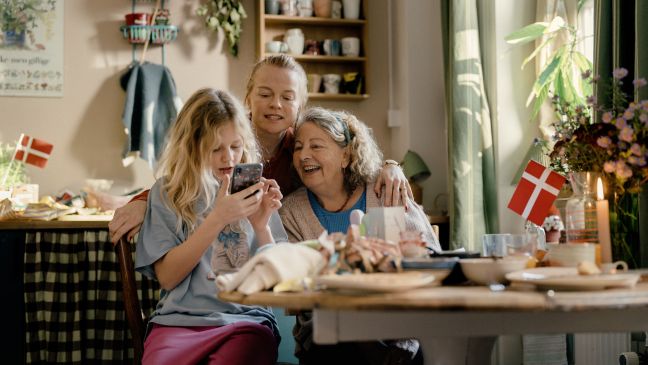 Mutter, Großmutter und Mira gucken interessiert auf das Handy