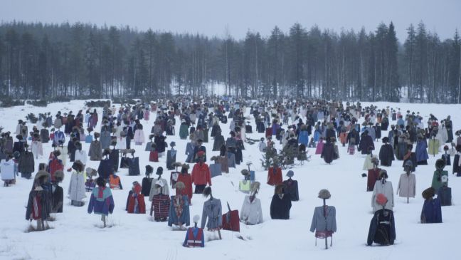 Kunstinstallation: zugeschneites Feld mit vielen Vogelscheuchen