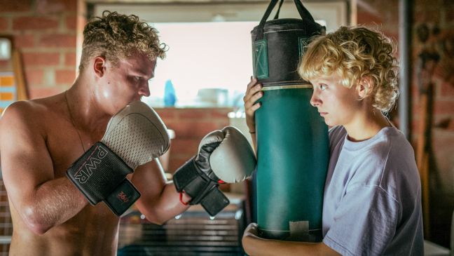 Malou hält den Boxsack und ihr Bruder Max boxt drauf