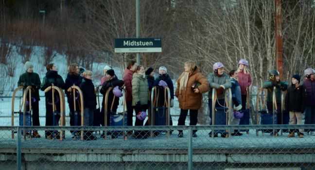 Viele Menschen mit Schlitten und Helmen stehen am Bahnsteig