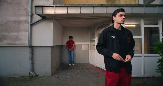Gentian und Altin vor dem Eingang eines Wohnhausblocks