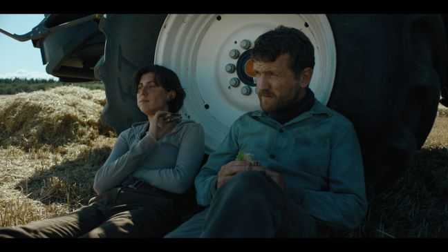 Erik und Astrid machen Pause im Schatten des Traktors