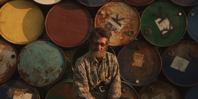 Der Protagonist vor Fässern mit Öl/Benzin