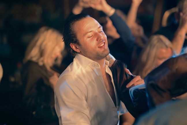 Oscar tanzt lächelnd und schwitzend in der Disco mit geschlossenen Augen
