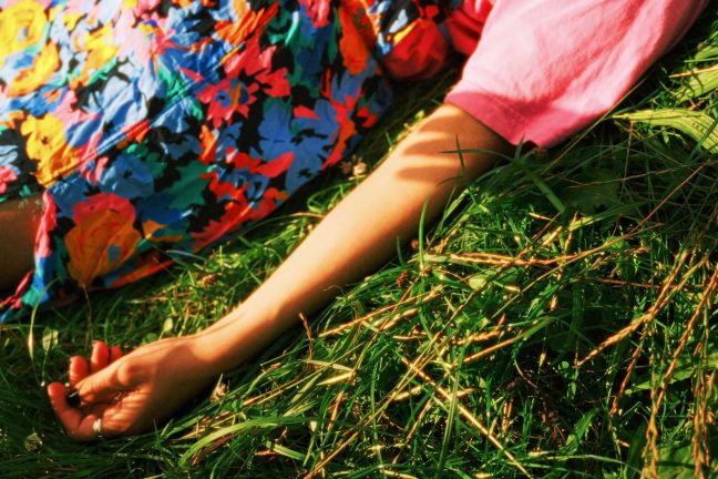 eine Frau im geblümten Kleid, Arm im Gras