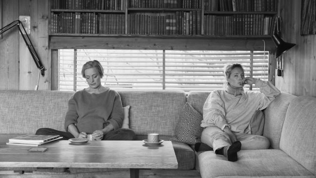 Mutter und Tochter sitzen mit Abstand auf dem Sofa