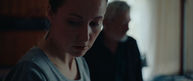 Miia schaut nach unten, im Hintergrund der Großvater