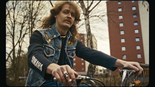 Ein Mann mit Schnauzer, Kutte und langen Haaren auf dem Rad