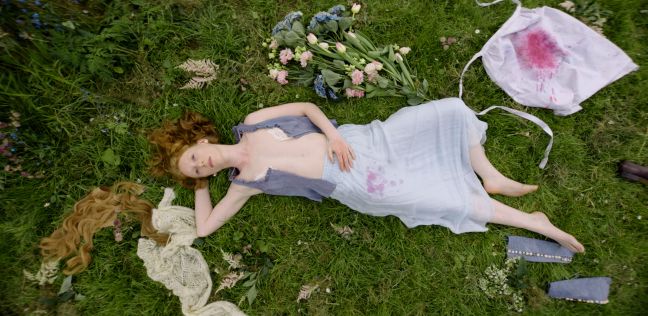 Nore liegt auf der Wiese, Extensions, Blumen und eine verschmierte Schürze neben ihr