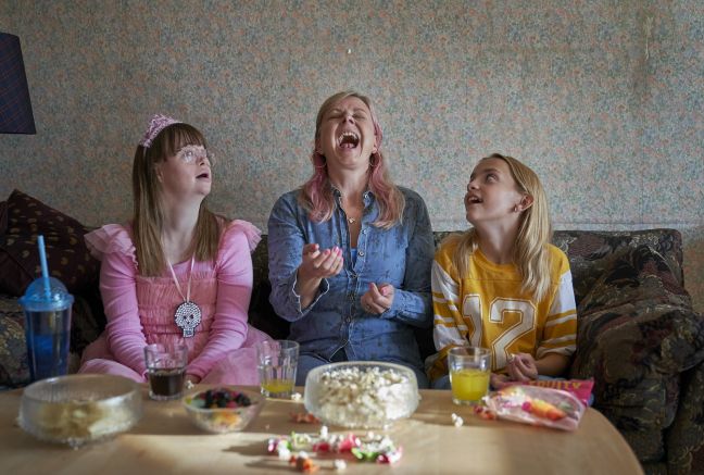 Sanne (Mutter) versucht ein Popcornkern zu fangen; Honey und Mikala (Schwester) gucken zu. Sitzen auf der Couch