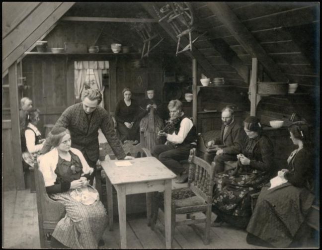 Menschen mit Handarbeit und Musikinstrumenten in einem Haus