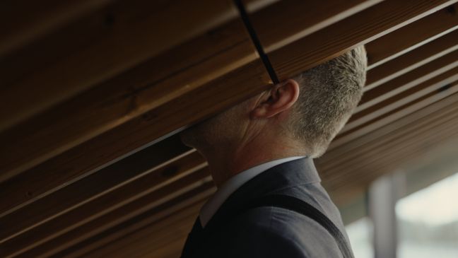 Der Mann steckt seinen Kopf zwischen zwei der vielen Holzbeklankungen der Wand