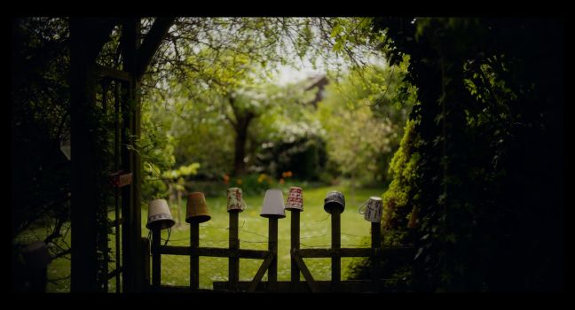 Blick in den Garten, auf der Holzpforte sind verschiedene Blumentöpfe gesteckt