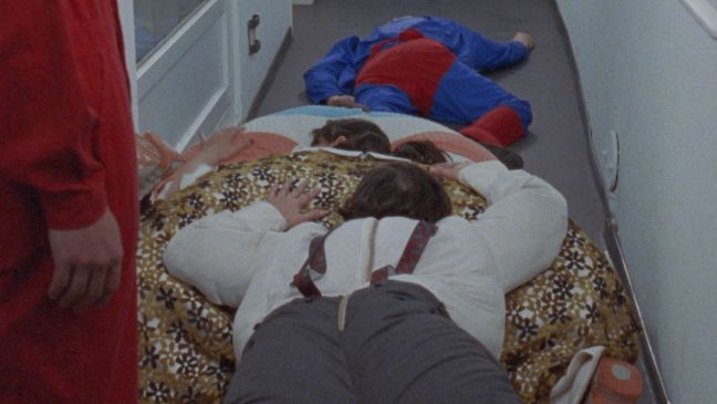 Mehrere Schauspieler liegen erschöpft aufeinander in Fat Suits