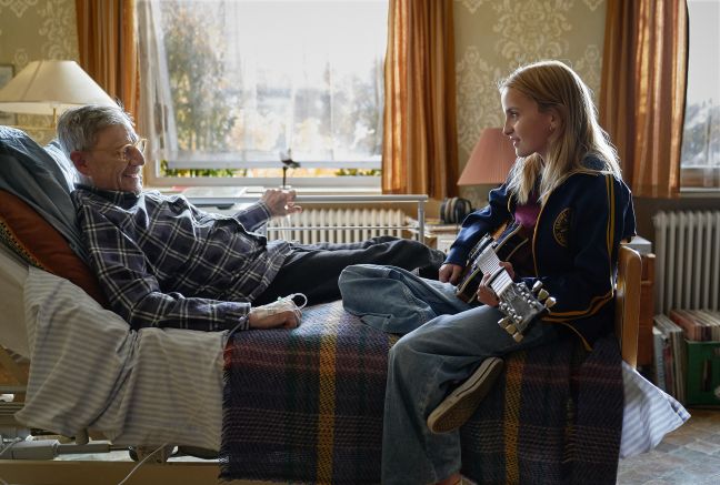 Honey (Haupf.) spielt Gittare, Marcel(Großvater) liegt auf dem Bett