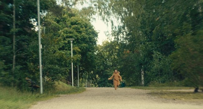 Ninni läuft barfuß in Onesie auf einem Sandweg