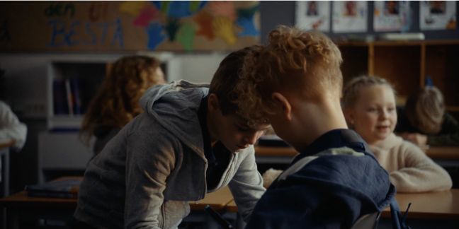 Ein Klassenkamerad schreibt etwas mit einem blauen Marker auf Theos Gipsarm