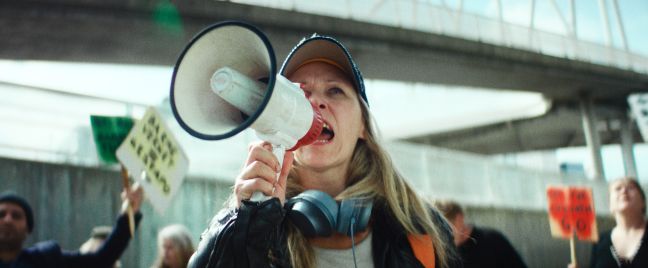 Agnes schreit durch ein Megaphon bei einer Demo