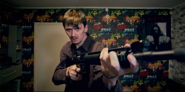 August steht in seinem Zimmer mit einem Gewehr