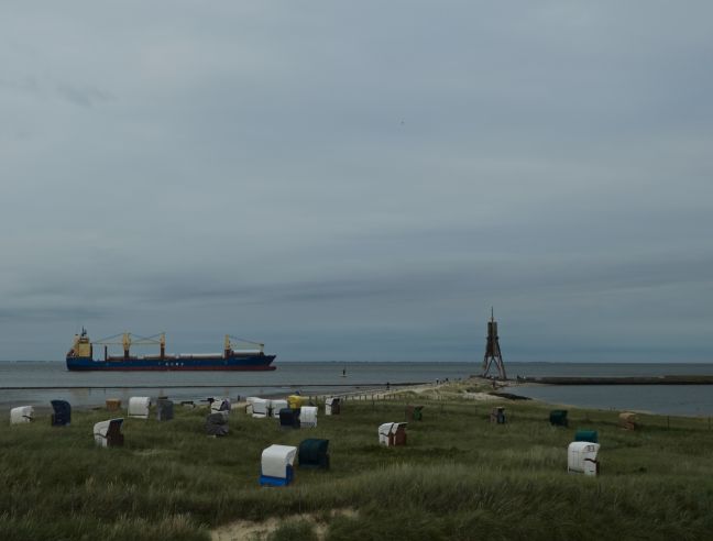 Düne mit Strandkörben, auf dem Meer ein Frachter