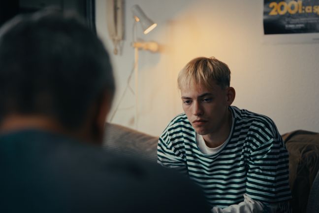 Jona auf einem Sofa, im Vordergrund sein Vater von hinten