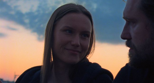 Ilona schaut Oleg liebevoll an, im Hintergrund der Sonnenuntergang