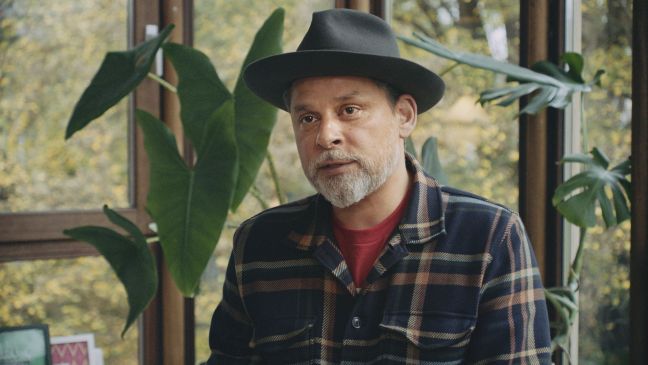 Jamil Shihab sitzt mit Hut am Fenster vor einer Pflanze