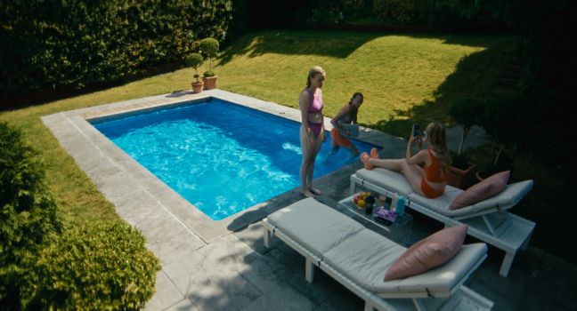 Luca steht mit dem Rücken zum Pool, ihre Eltern um sie herum