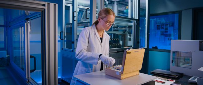 Marie arbeitet mit Proben und Messwerkzeugen aus einem Holzkoffer