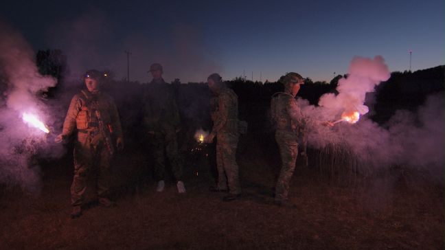 4 Männer in Uniform mit Pyrotechnik auf einem Feld