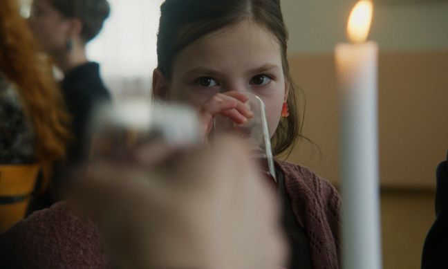 Nahaufnahme Mare (Hauptdarstellerin), sitzt am Tisch und trinkt Saft
