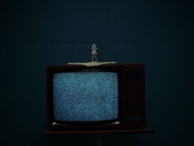 analoger Fernseher mit Rauschbild und einer kleinen Figur darauf