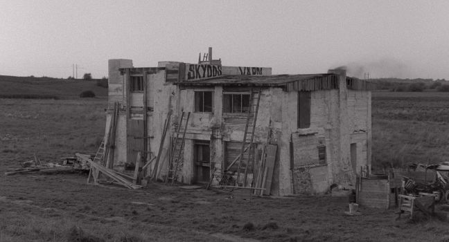 Das Gebäude von außen, mehrere Stapel Holz darum herum