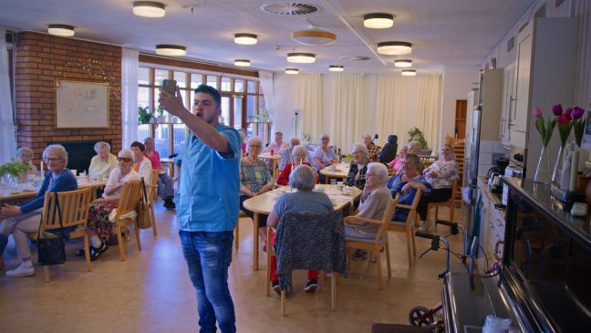 Majd nimmt ein Video mit seinem Smartphone auf im Essenssaal der Pflegeeinrichtung