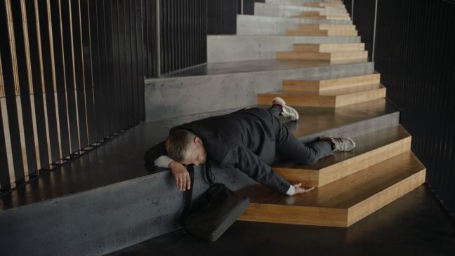 Der Mann liegt auf dem ersten Plateau einer Treppe, seine linken Gliedmaßen hängen herunter