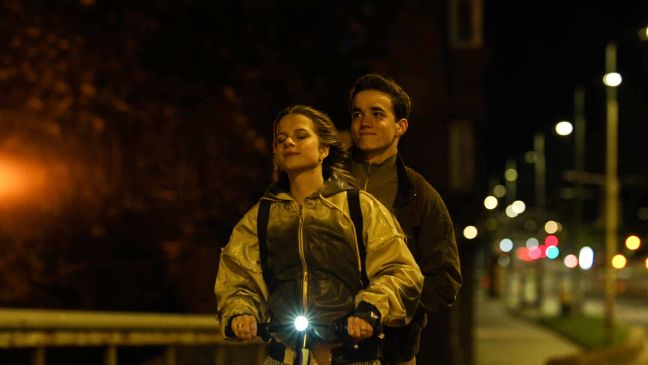 Miia und Morten auf einem Roller, fahren nachts durch die Stadt